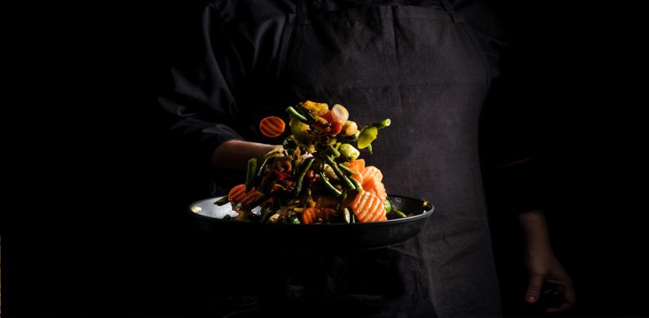 Chef cooking colorful vegetables in a pan