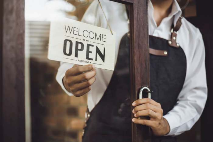 uproar chicago restaurant opened Store owner turning open sign broad through the door glass and ready to service.