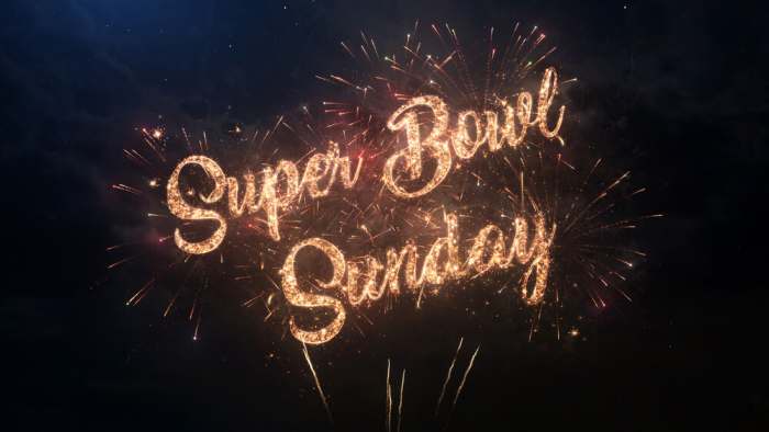 Super Bowl Sunday greeting text with particles and sparks on black night sky with colored slow motion fireworks on background, beautiful typography magic design.
