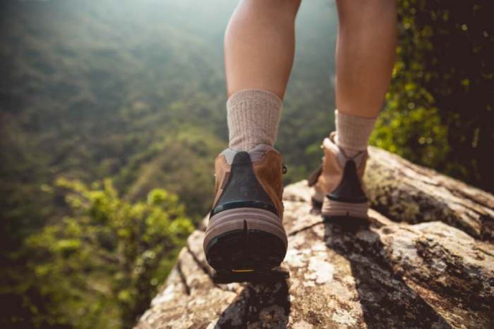 man walking in nature wearing a pair of hiking boots ands socks