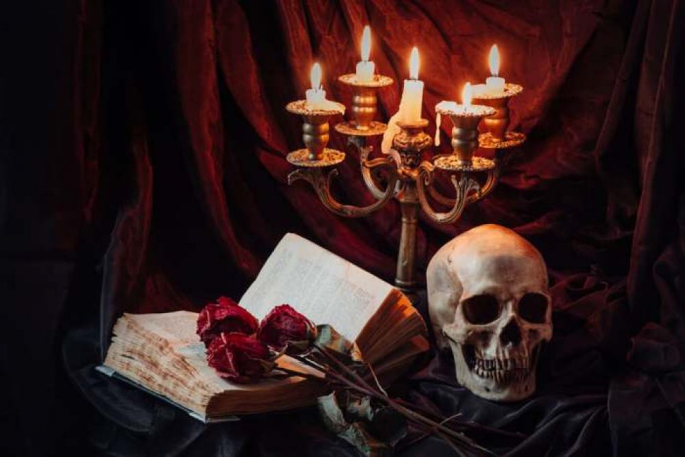 Gothic scene with an image of a skull, an open book and red roses