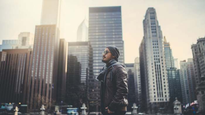 A young man standing with beautiful buildings background before sunset at Chicago city : films grain concept